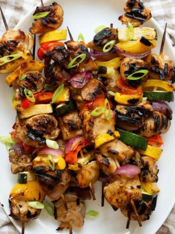 Grilled honey soy chicken kebabs served on a platter with colorful veggies, lightly charred and glossy from the miso marinade