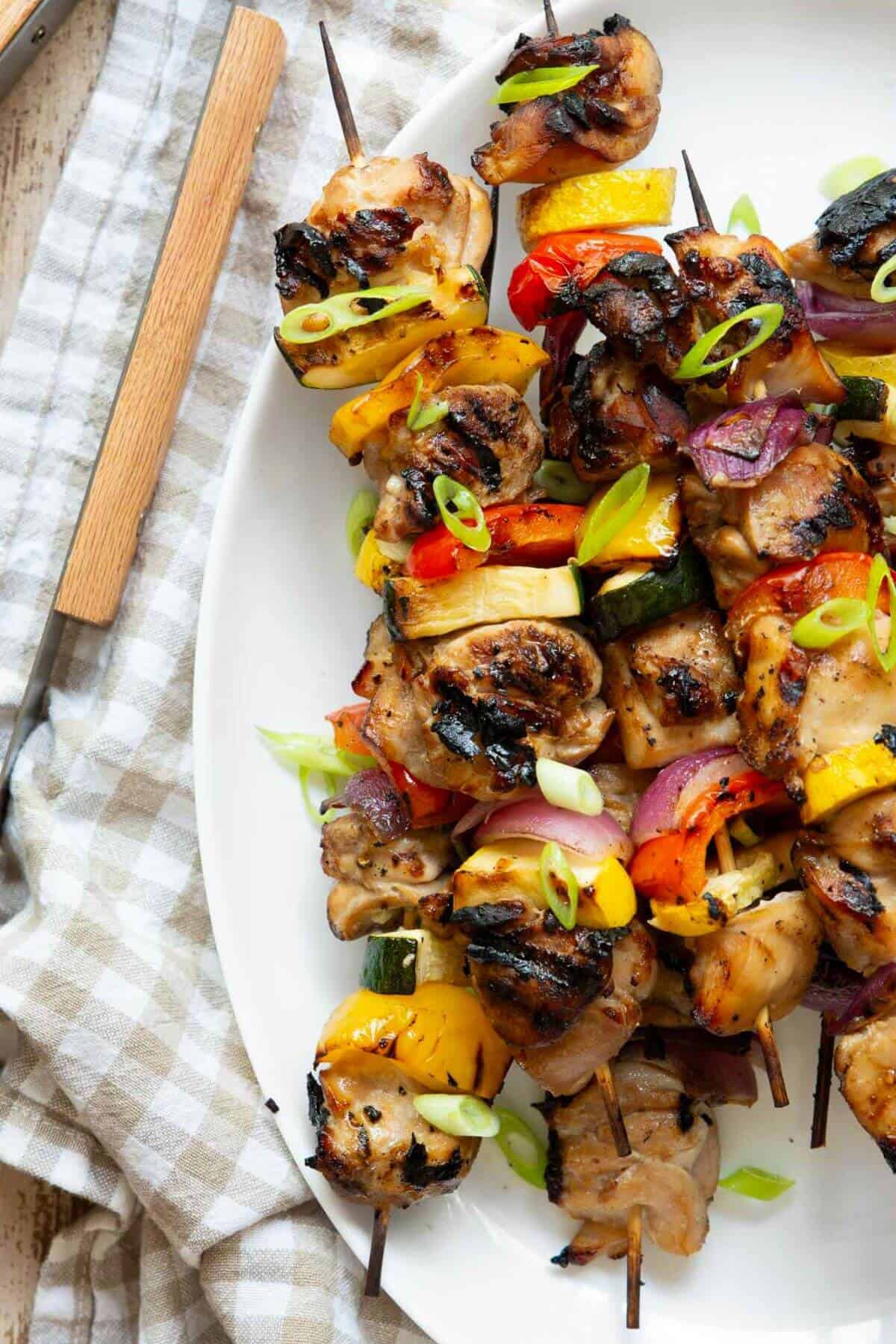 Grilled honey soy chicken kebabs with colorful vegetables on a serving platter, lightly charred and ready to serve