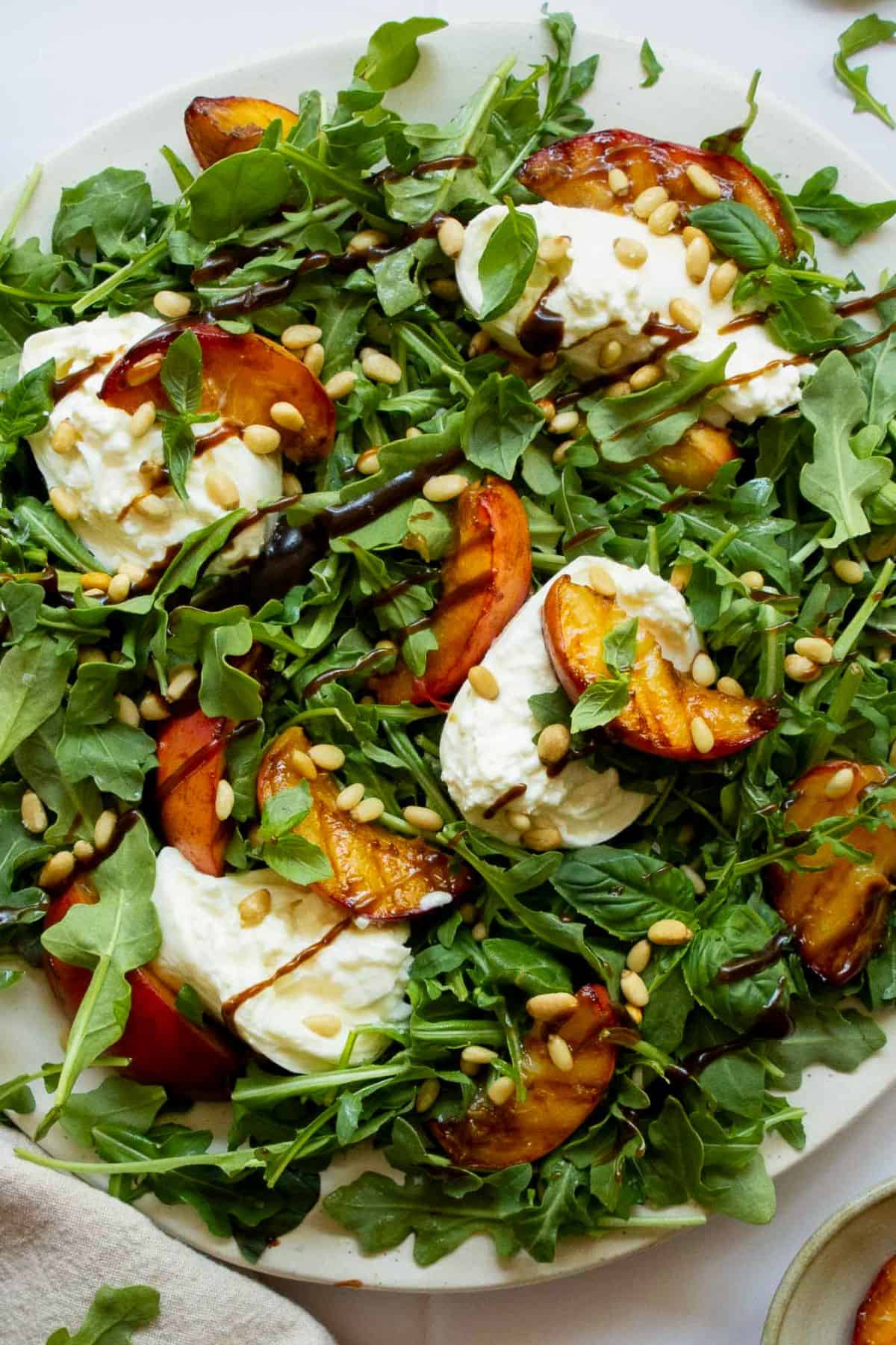 Summer grilled peach and burrata salad with fresh basil, arugula, pine nuts, and balsamic glaze