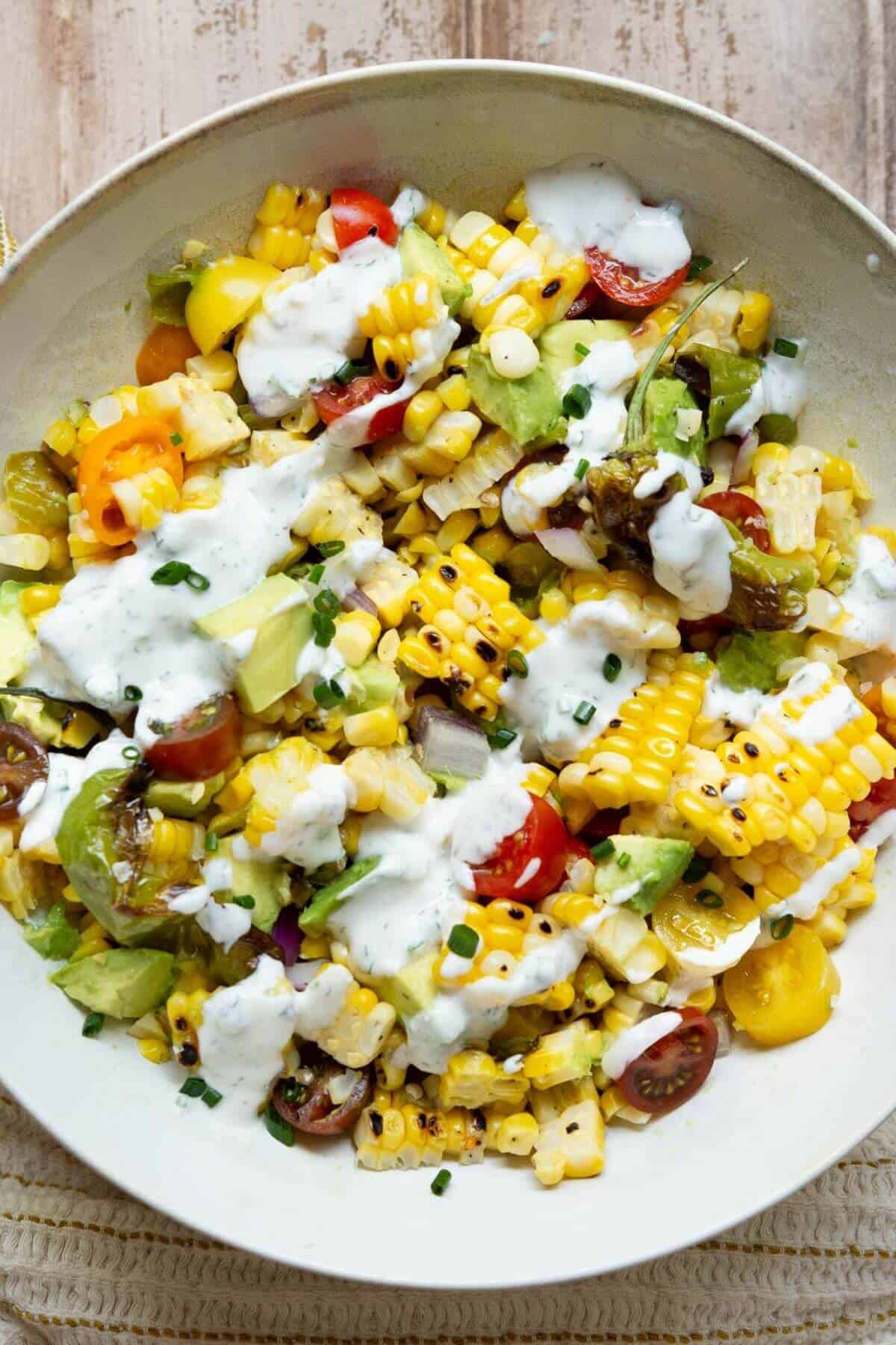Yogurt ranch dressing being drizzled over the grilled corn salad