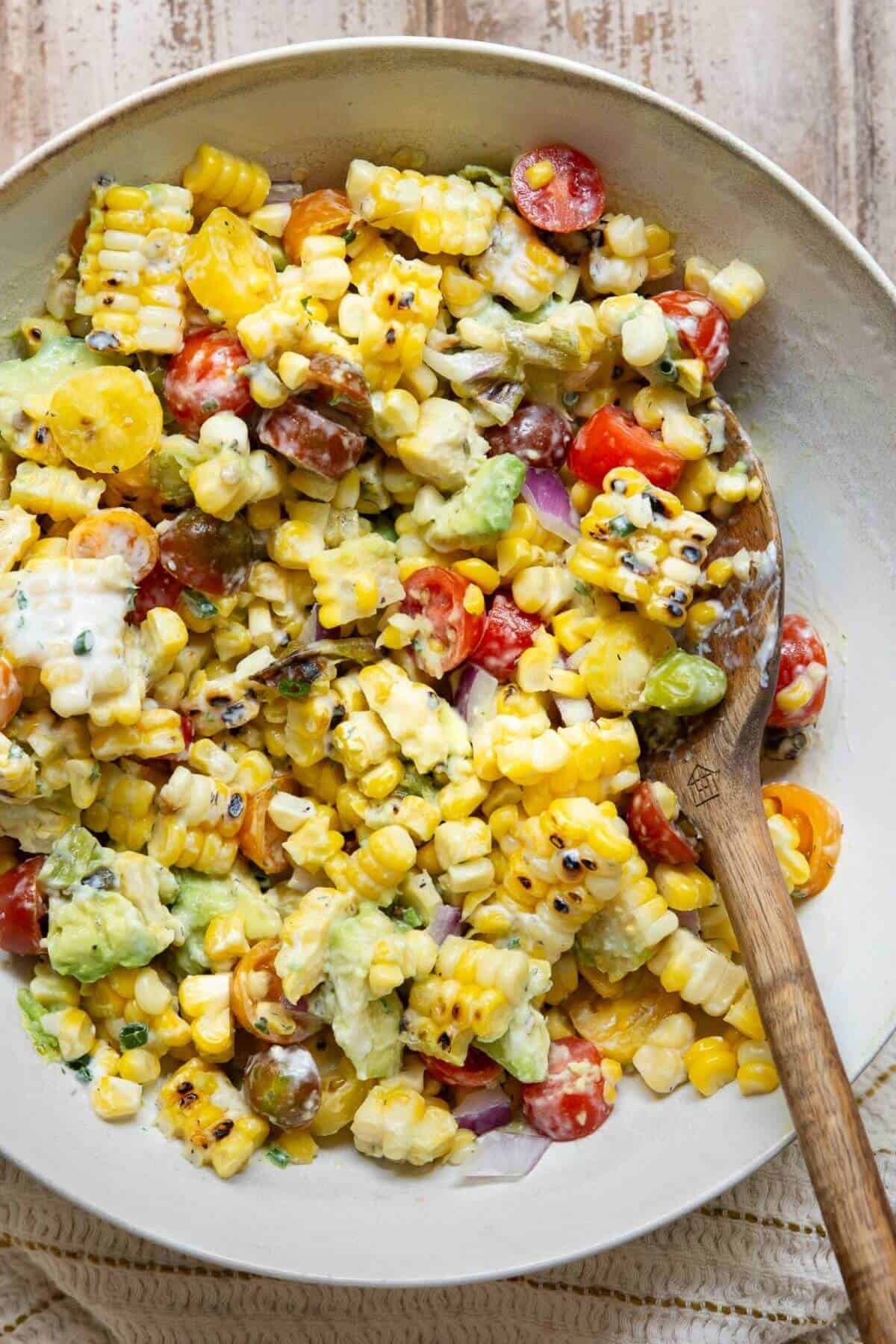 Summer avocado corn salad tossed with charred corn, grilled shishito peppers, avocado, tomatoes, red onion, and creamy yogurt ranch dressing