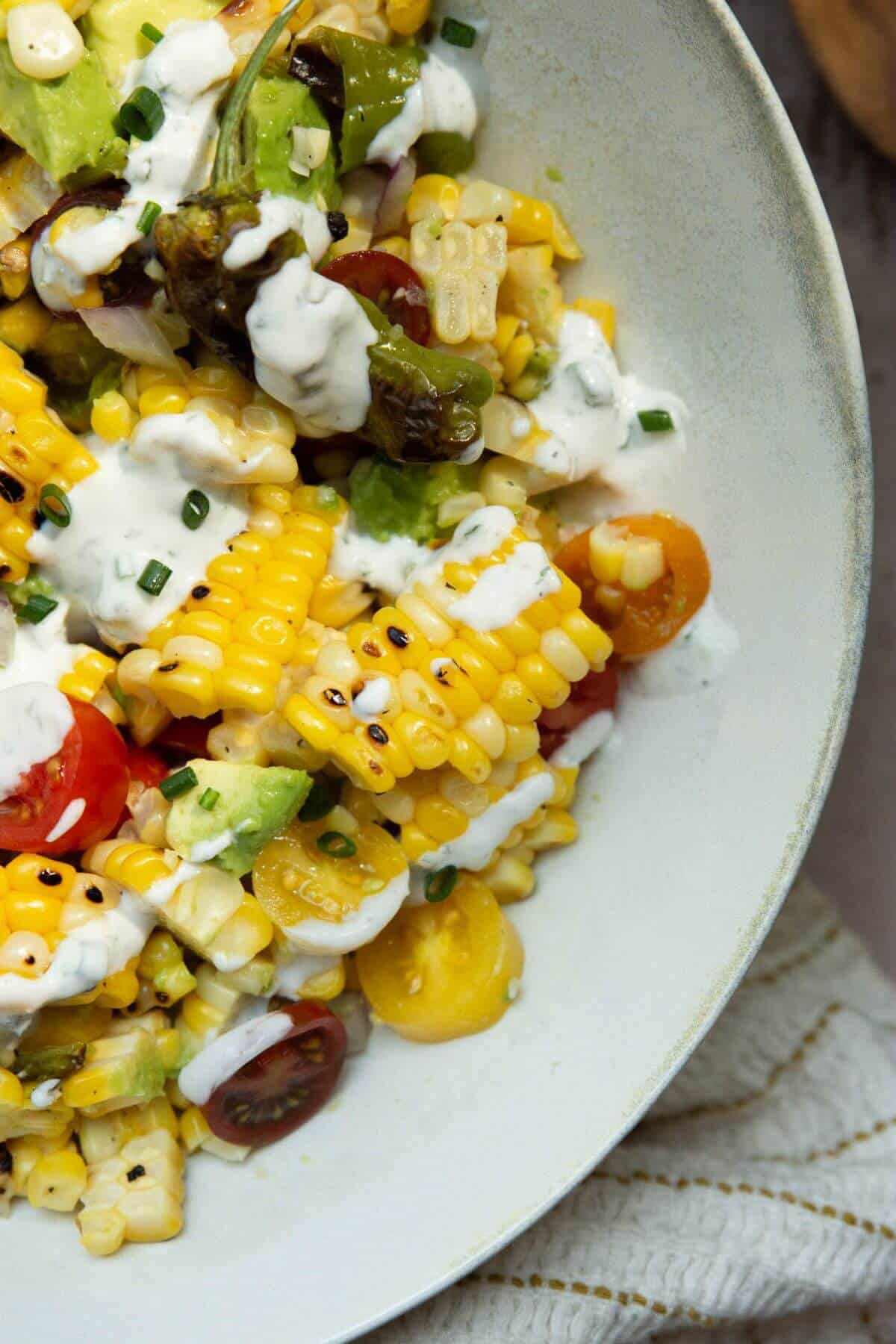 summer corn salad with tomatoes, onion, avocado and shishito peppers