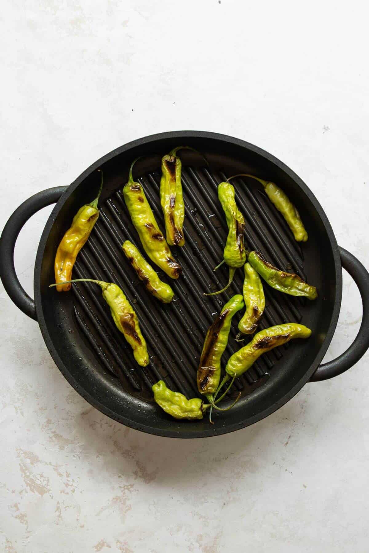Shishito peppers blistering on a hot grill.