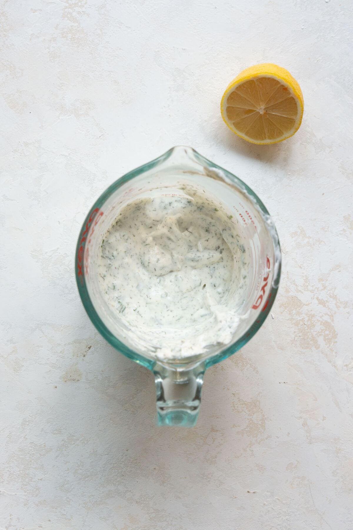 Small bowl filled with creamy Greek yogurt ranch dressing with herbs mixed in.