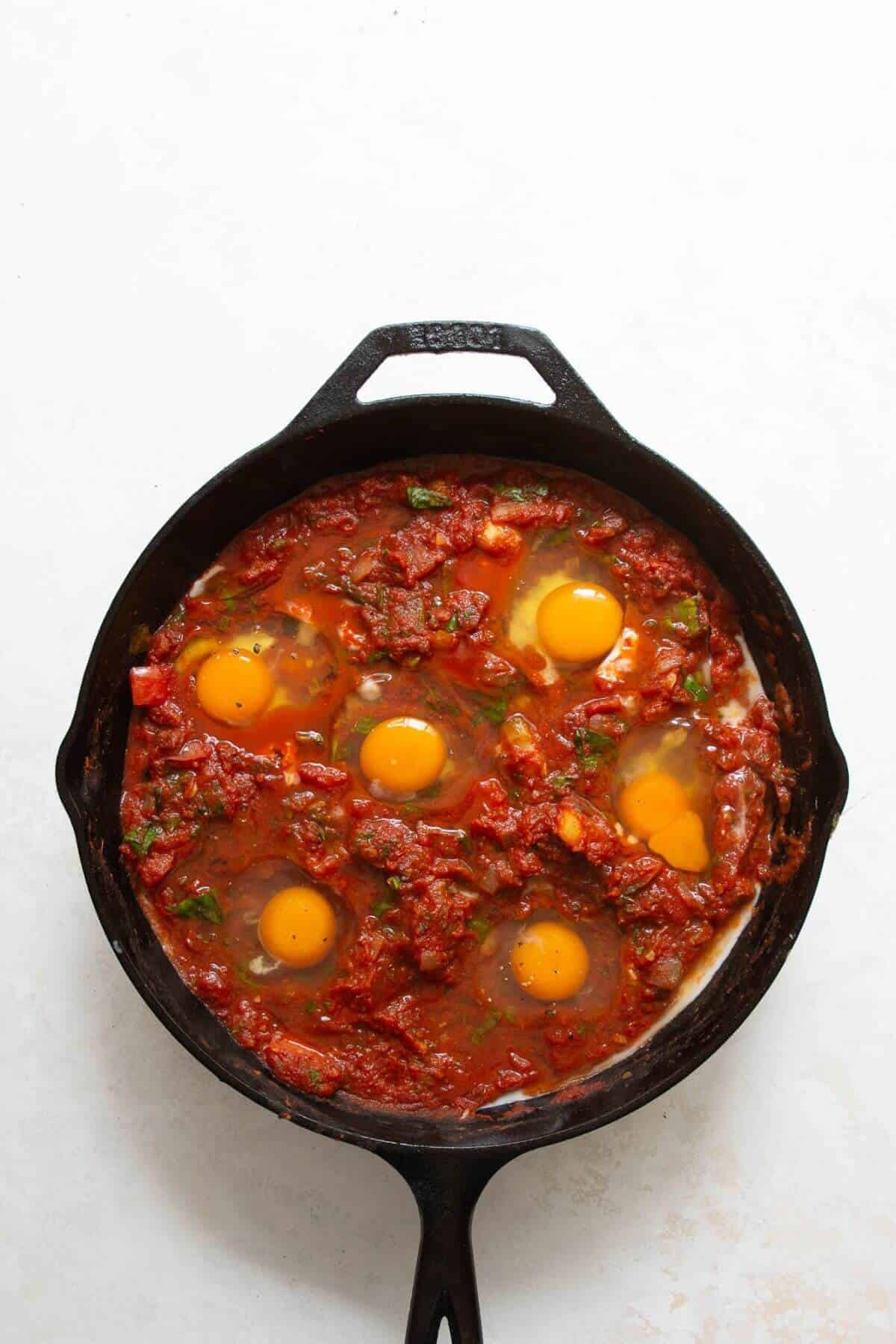 Cracking eggs into wells in the tomato sauce for shakshuka
