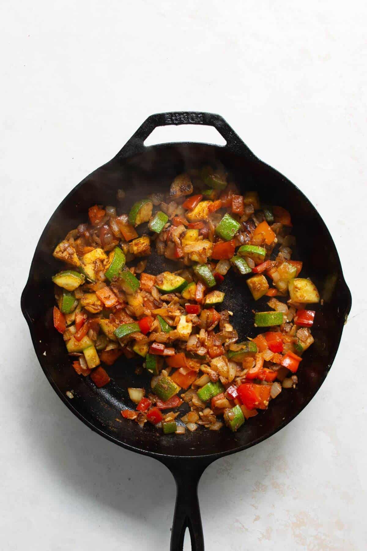 Adding cumin, paprika, ginger, and chili flakes to sautéed vegetables for shakshuka
