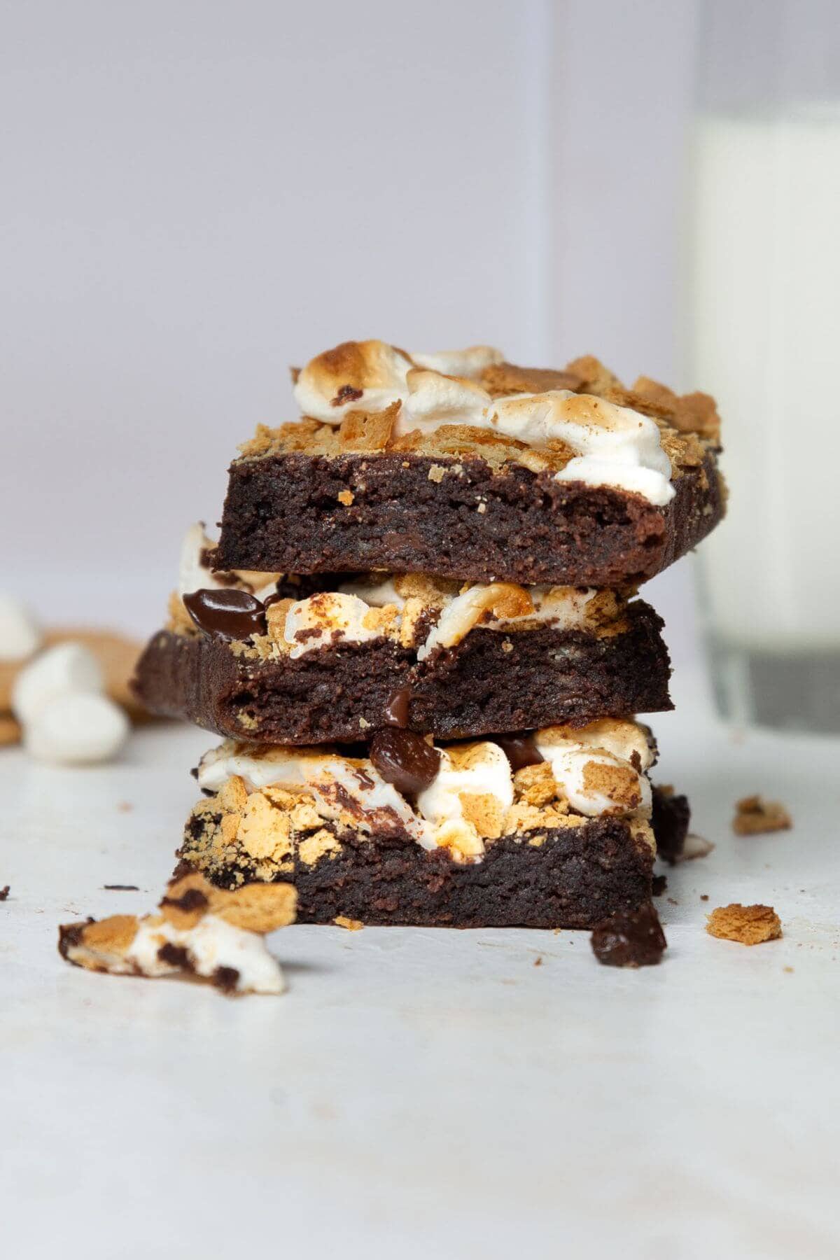Stack of three fudgy s'mores brownies with golden toasted marshmallows and crumbled graham crackers.