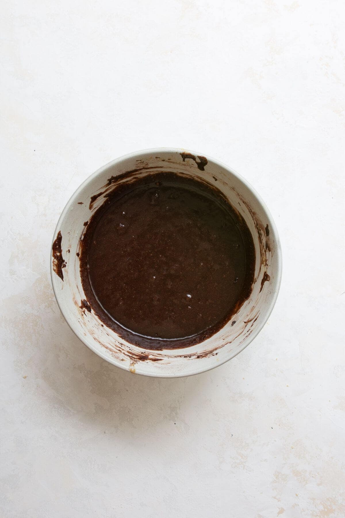 Adding almond flour, cocoa powder, and salt to wet ingredients in a mixing bowl for healthy s'mores brownies.