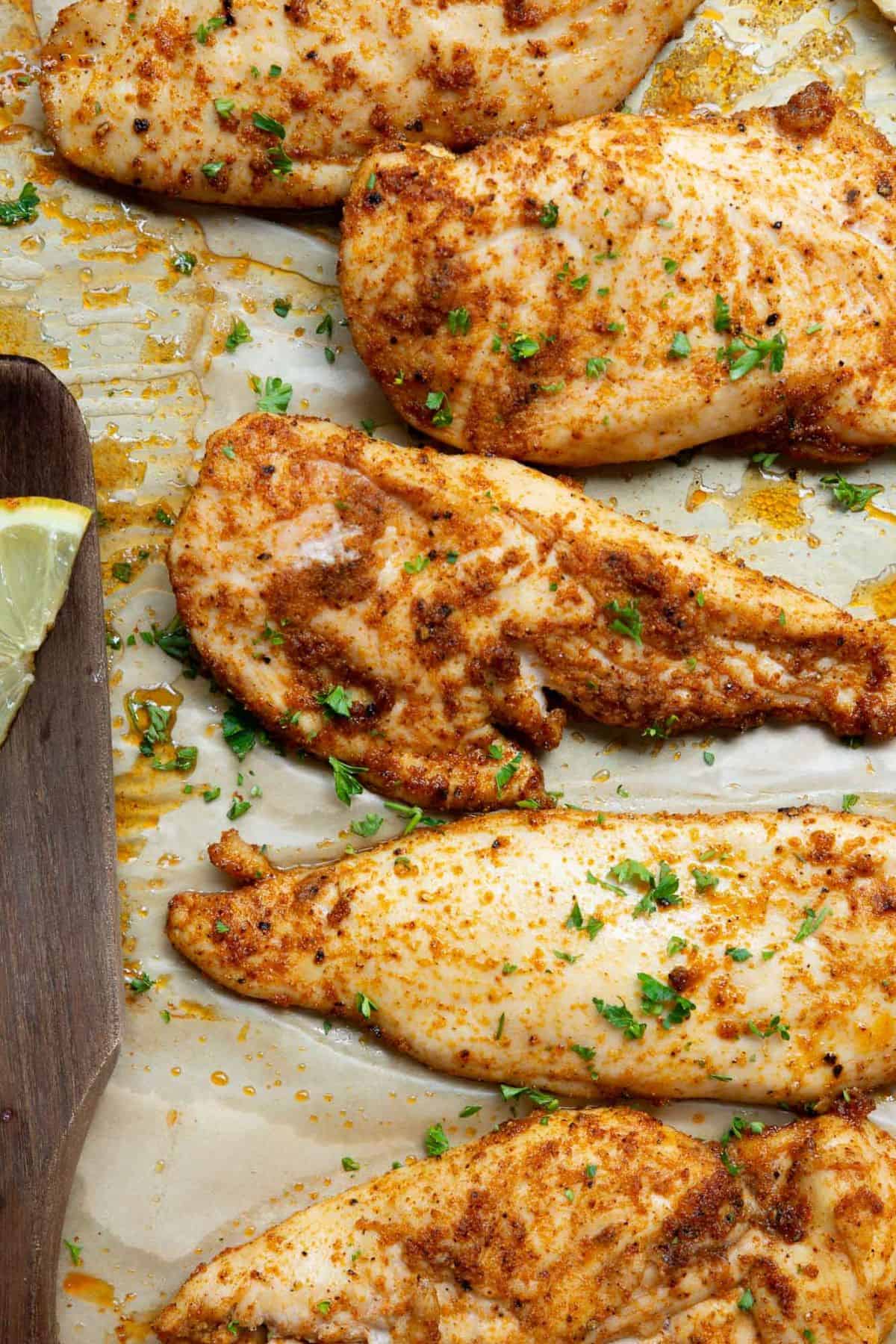 Flavorful thin sliced chicken breast seasoned with garlic, onion, and paprika on a baking pan.
