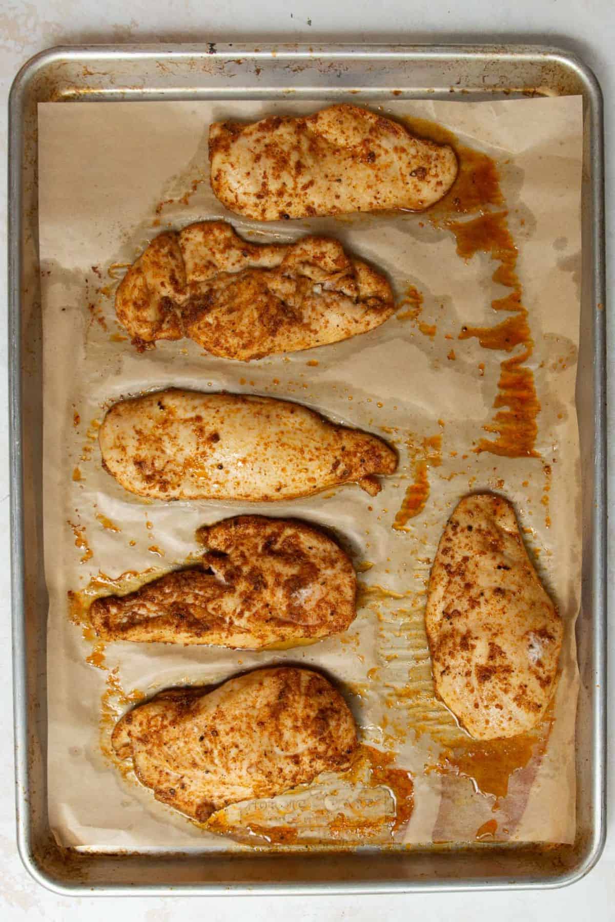 Perfectly baked thin-sliced chicken breast on a baking sheet, golden and juicy.
