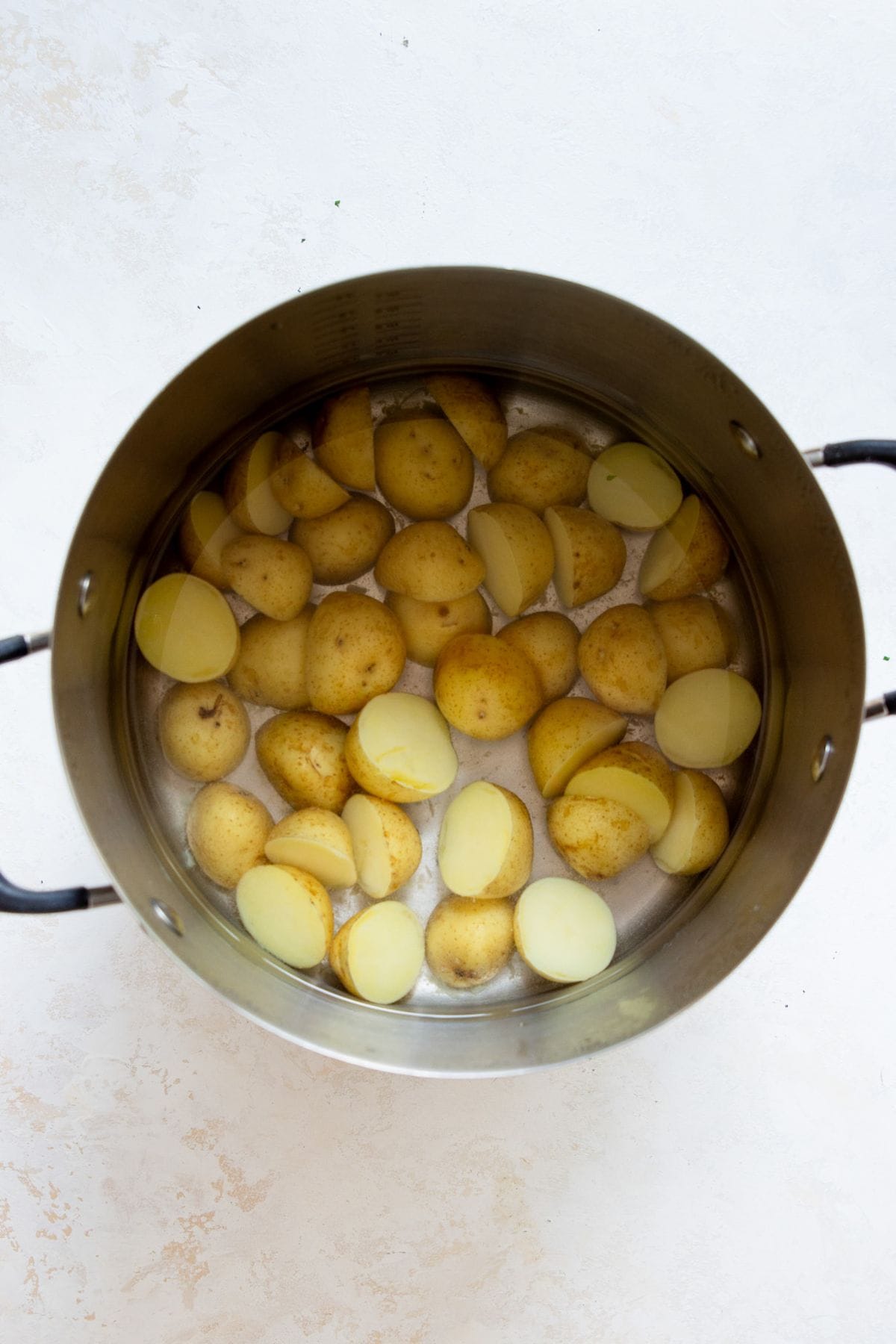 Halved Yukon Gold potatoes boiling in a pot of salted water for crispy potato salad.