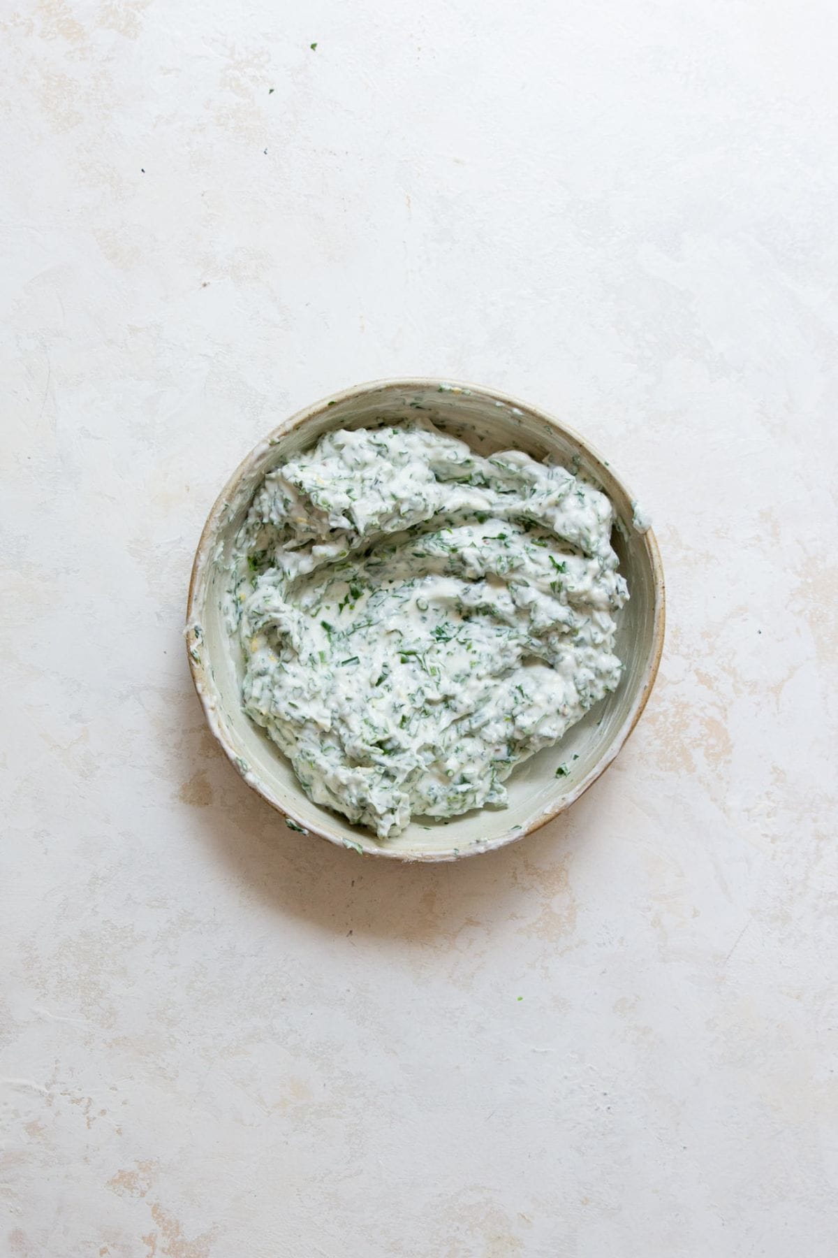 Creamy herb yogurt dressing in a bowl, made with Greek yogurt, fresh herbs, garlic, and lemon juice for crispy potato salad.