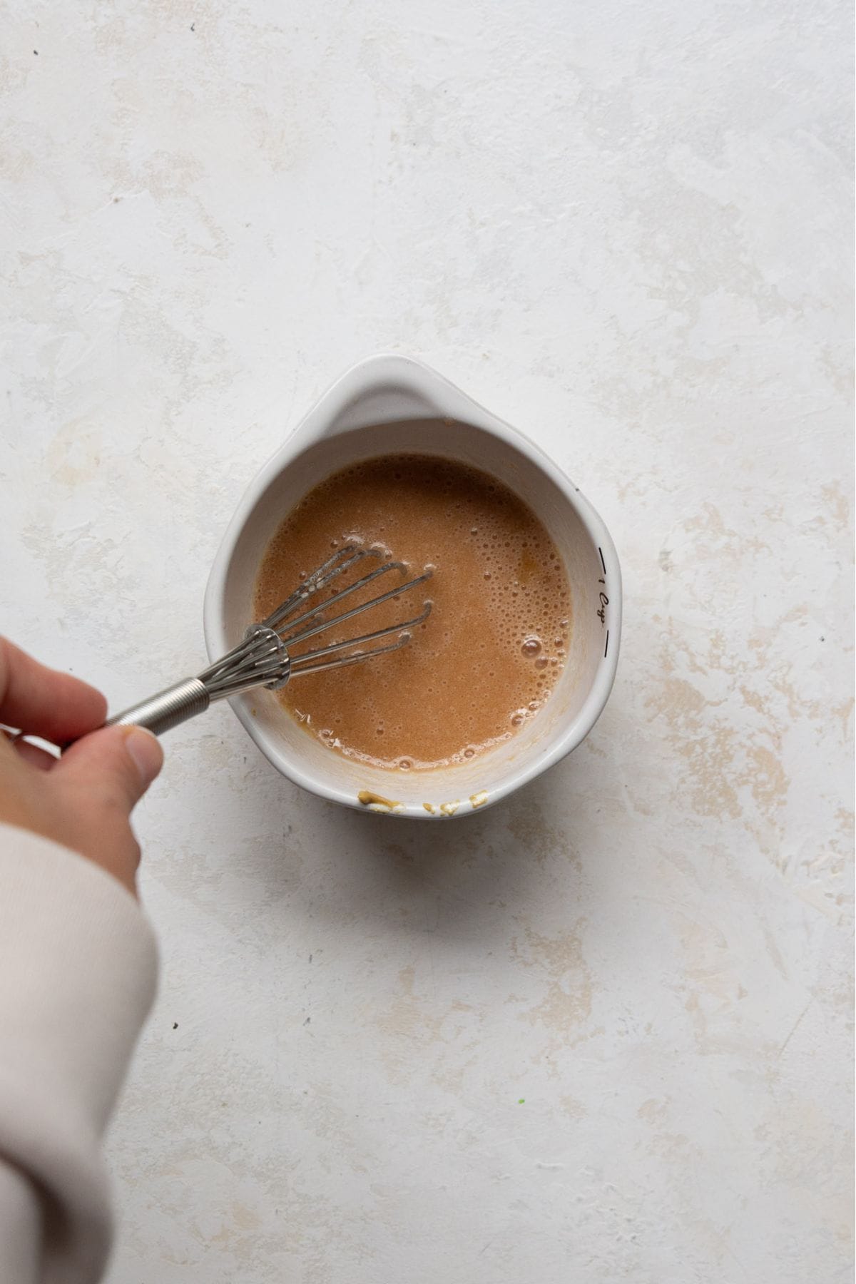 whisking lemon honey Dijon dressing together in a small bowl