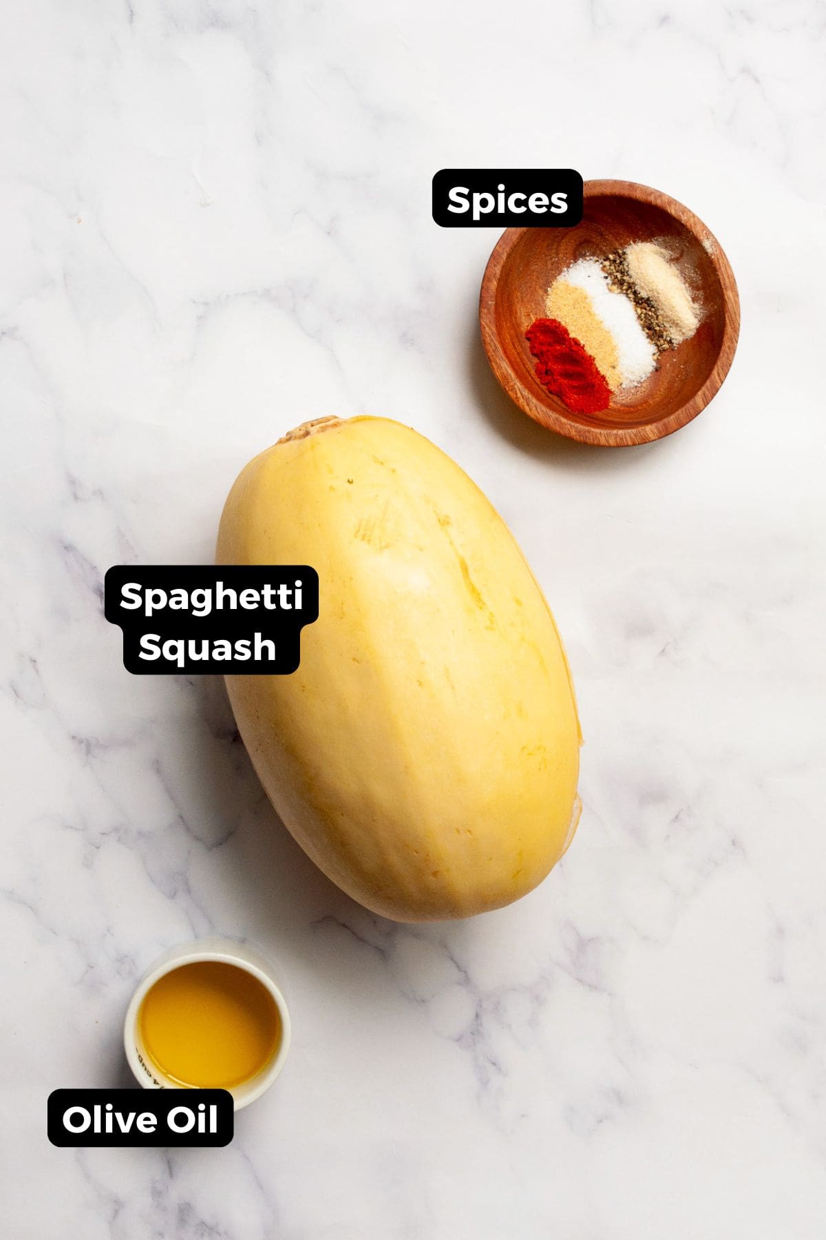 All labeled ingredients for air fryer spaghetti squash, including spaghetti squash, olive oil, salt, black pepper, garlic powder, onion powder, and paprika.