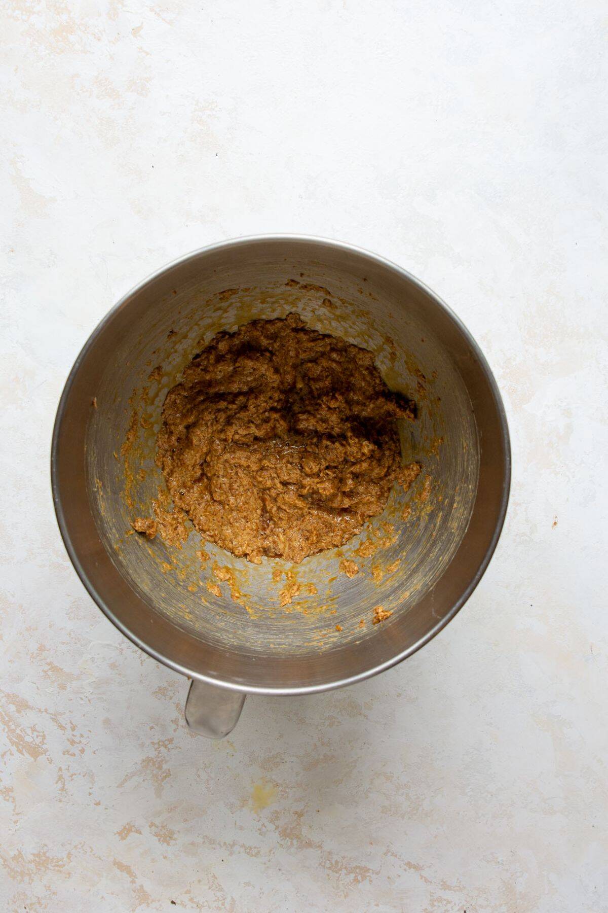 Creaming butter, coconut sugar, and maple syrup with an electric mixer, then adding egg and vanilla for cowboy pretzel cookies.