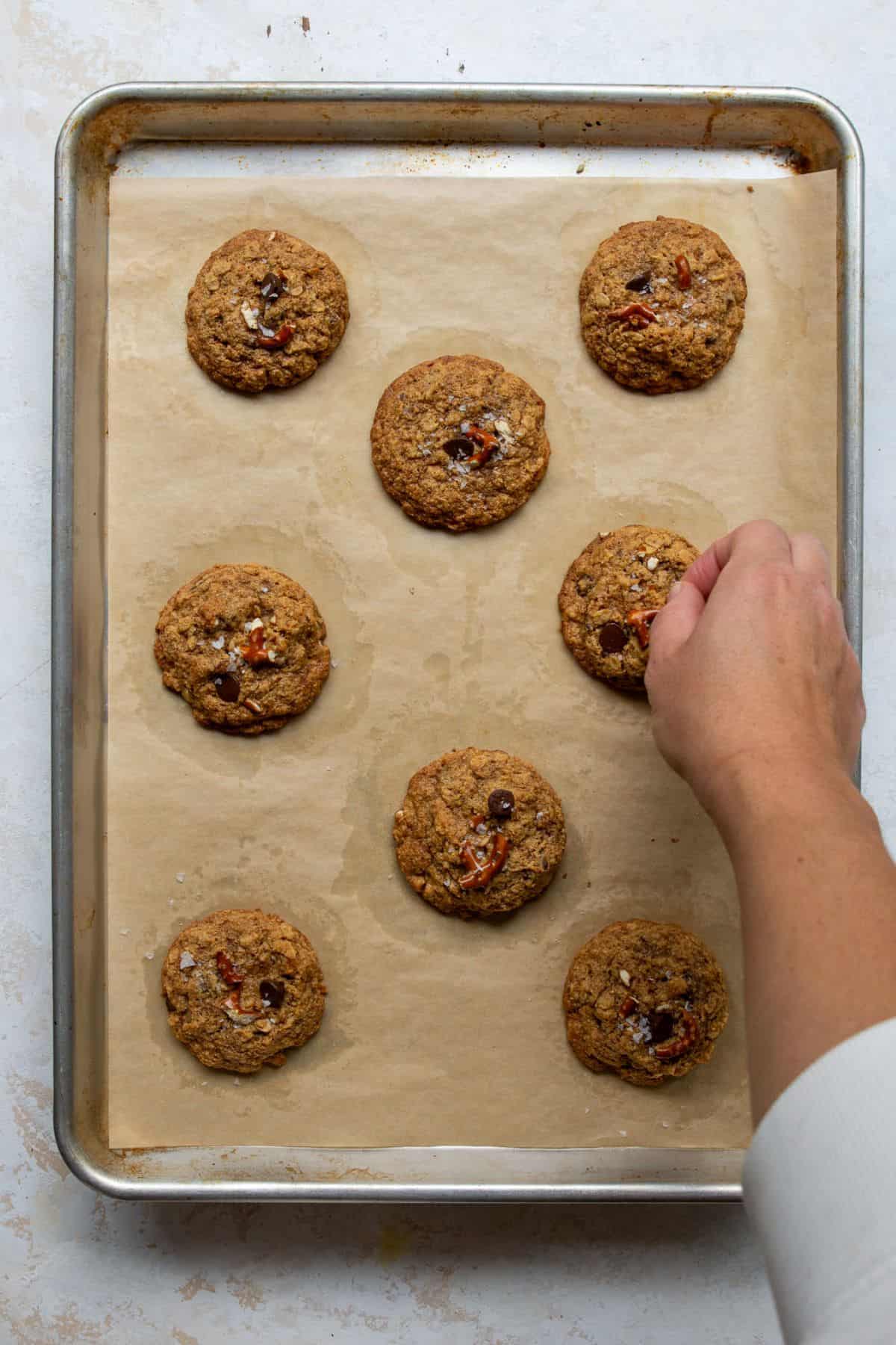 Sprinkling flaky sea salt on warm healthy cowboy pretzel cookies.