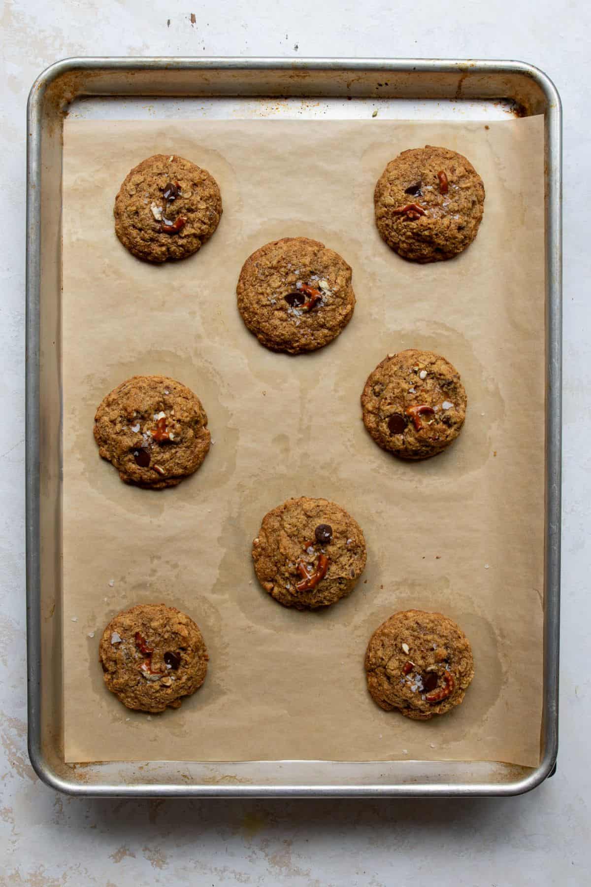Freshly baked cowboy pretzel cookies with sea salt on top on a parchment-lined baking sheet.