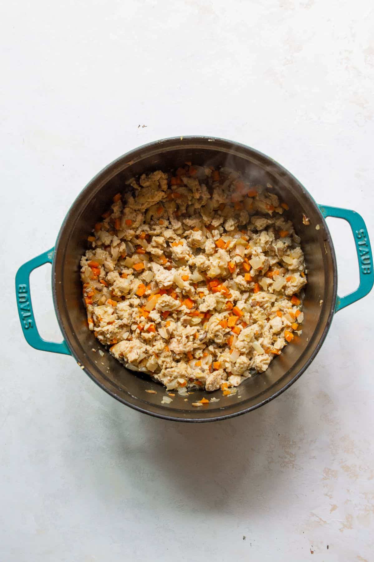 Ground chicken and veggies sautéing in Dutch oven pot.