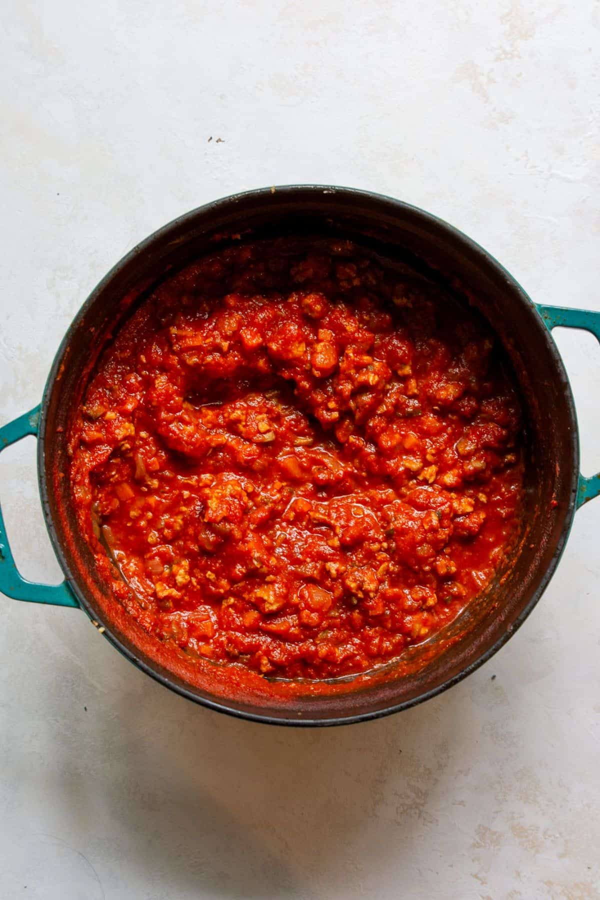 Rich, hearty chicken bolognese sauce simmering in a pot, made with ground chicken, mushrooms, and tomatoes.
