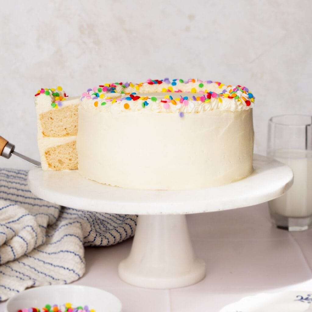 Soft, moist healthy vanilla birthday cake sweetened with maple syrup and topped with light vanilla buttercream and colorful sprinkles.