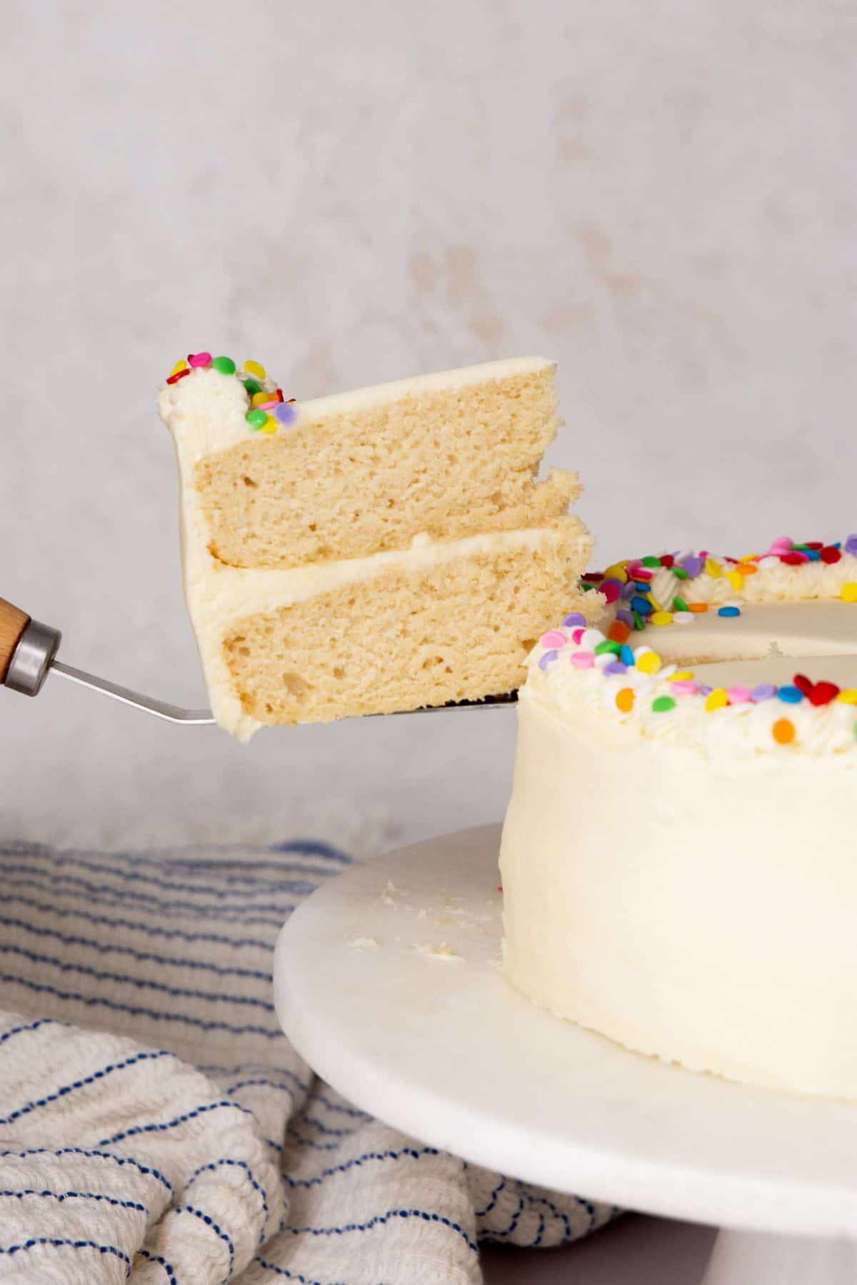 Slice of healthy vanilla birthday cake showing soft, fluffy layers and creamy vanilla frosting.