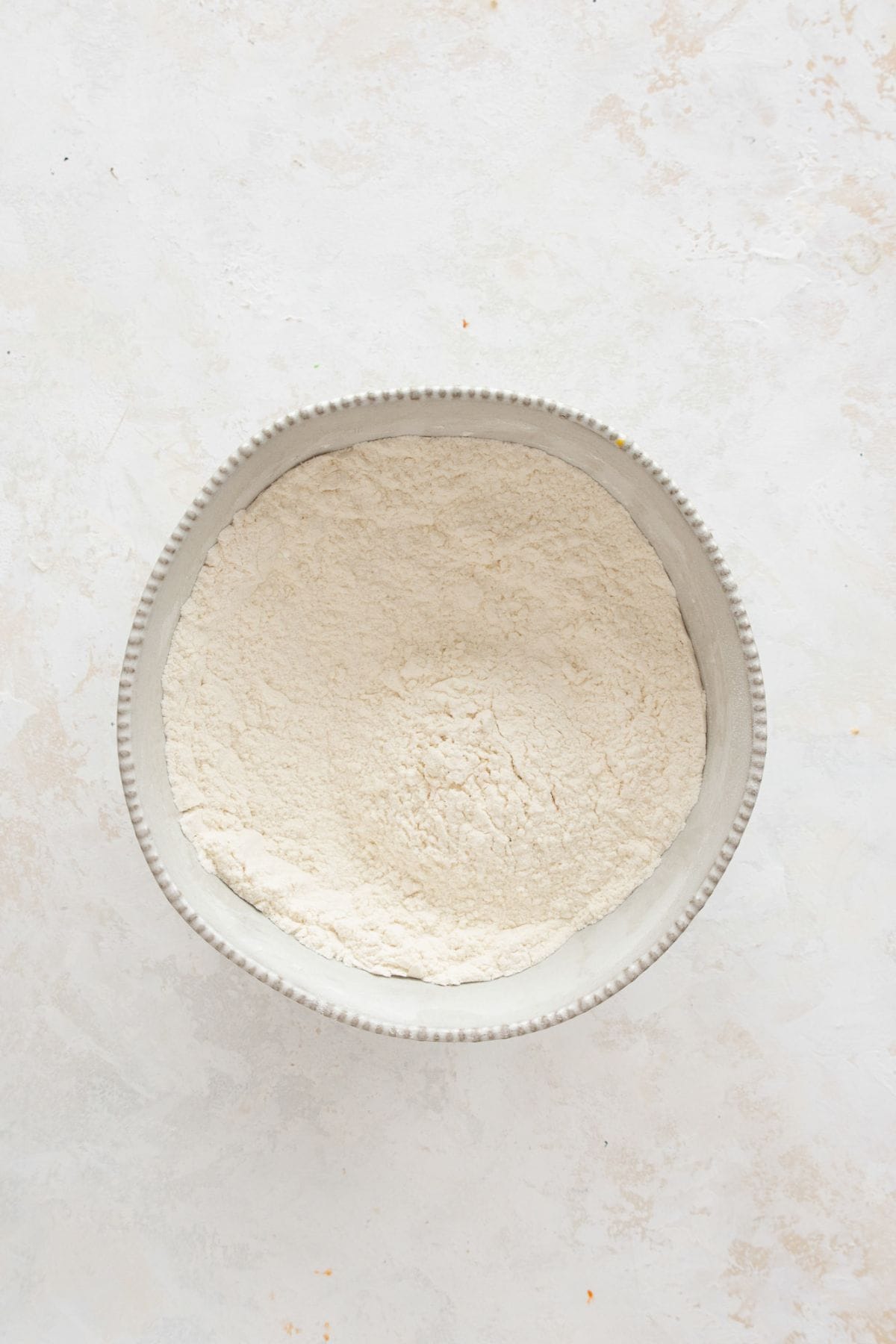 Whisking flour, baking powder, baking soda, and salt together in a mixing bowl for healthy vanilla cake batter.