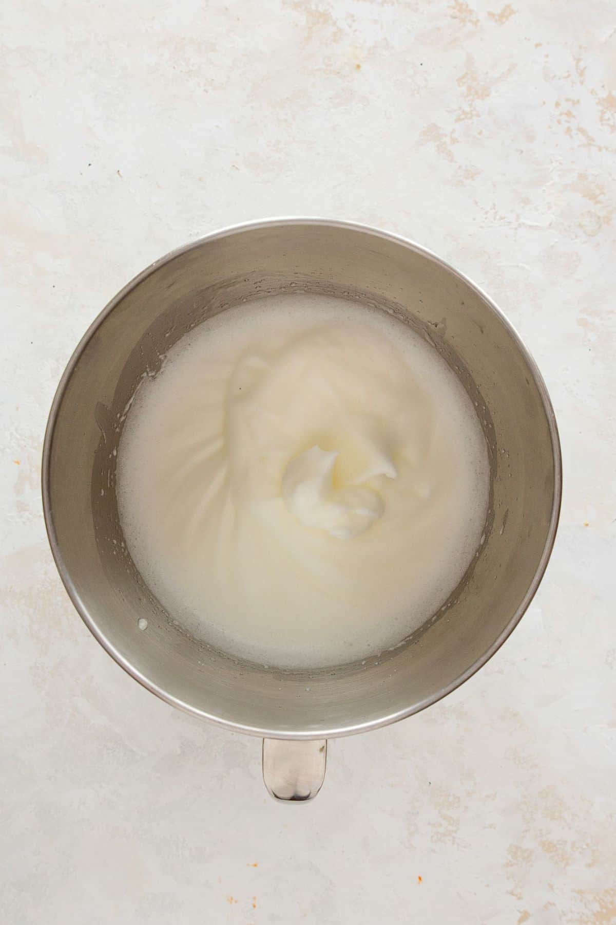 Beating egg whites to stiff peaks in a stand mixer for a light and fluffy healthy vanilla cake texture.