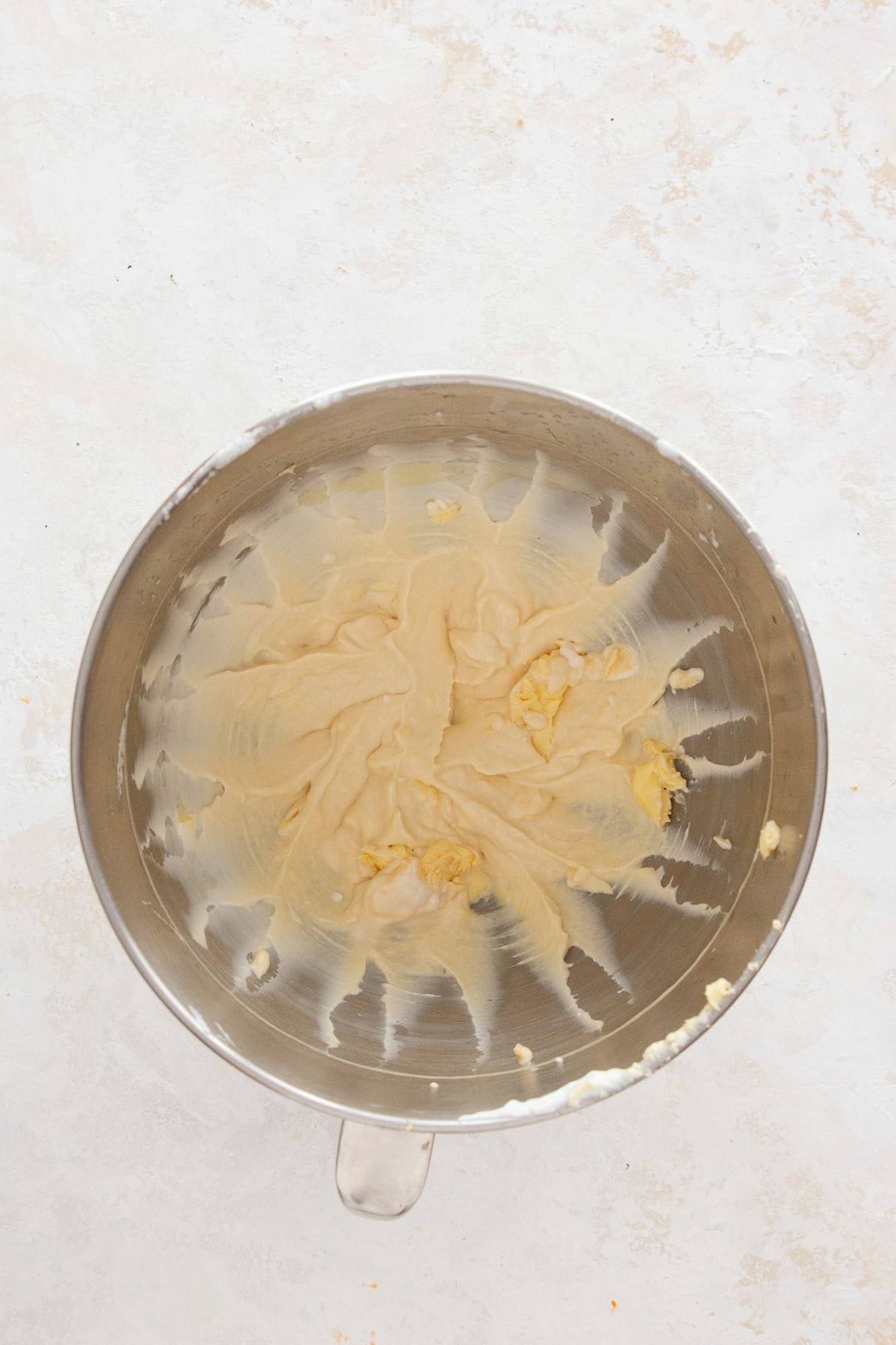 Creaming butter and Greek yogurt together in a mixing bowl until smooth for the healthy vanilla cake base.