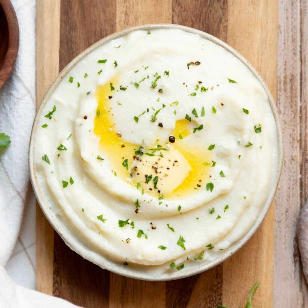 Super fluffy and creamy mashed cauliflower with butter, black pepper, and herbs.