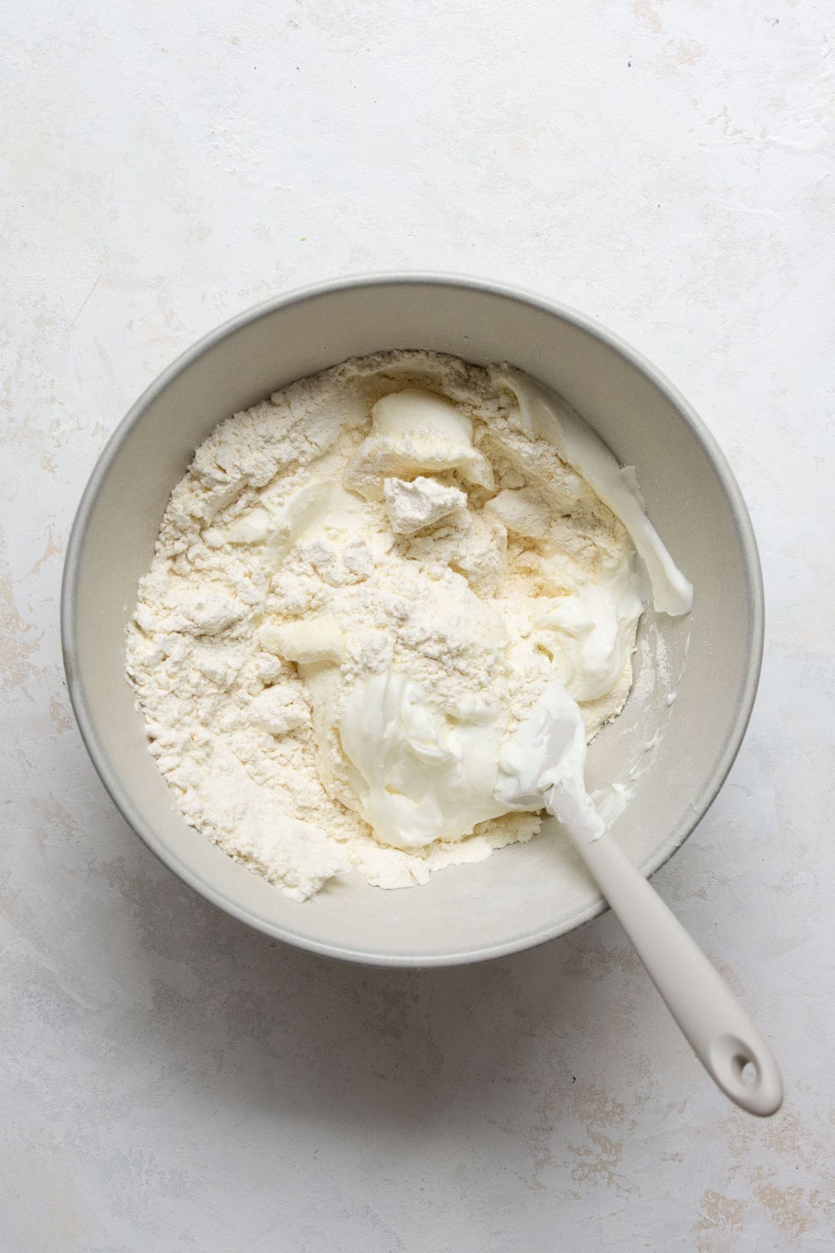 Mixing self-rising flour and Greek yogurt in a bowl to form healthy, high protein pizza dough.