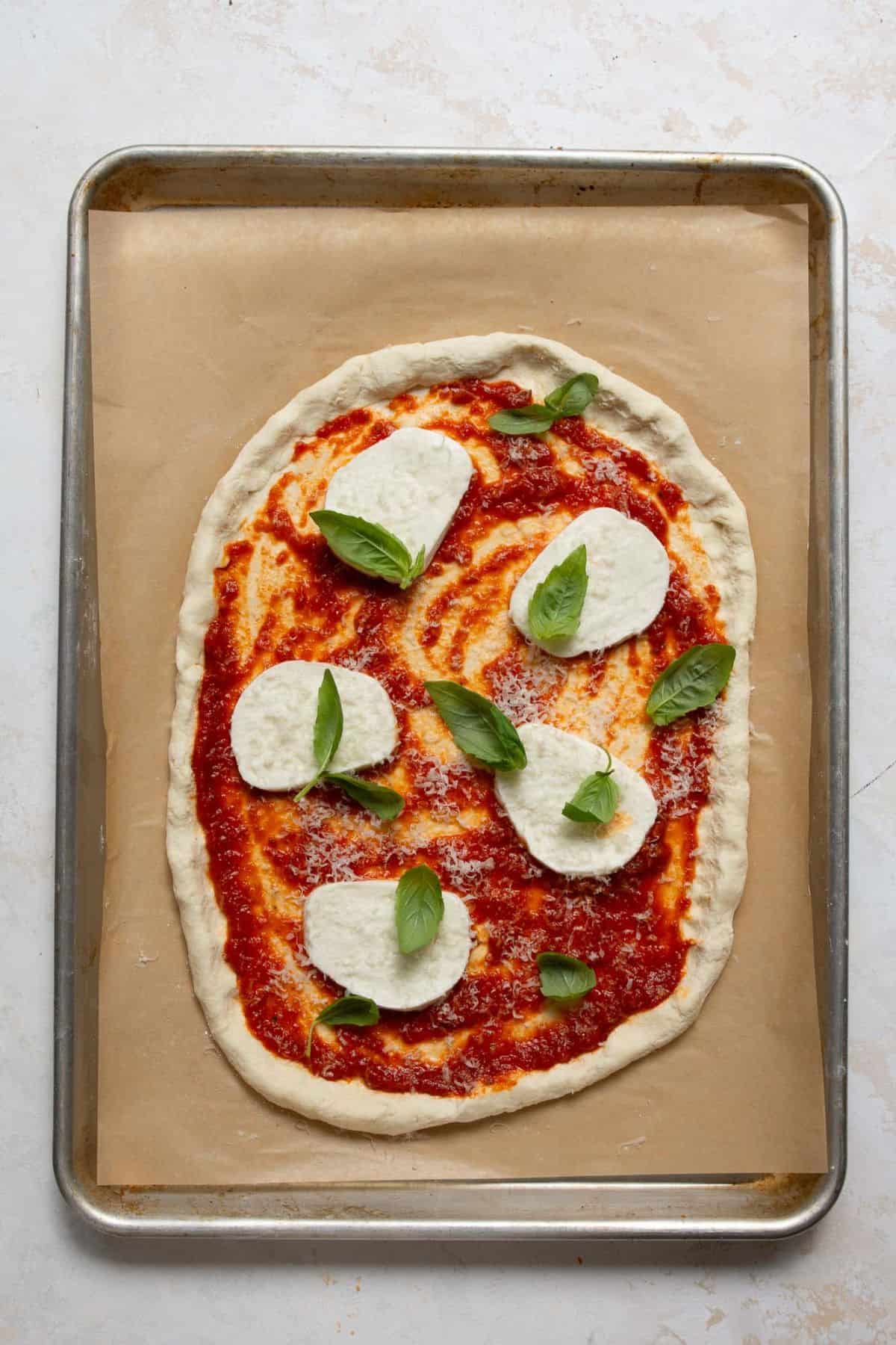 Healthy pizza topped with fresh mozzarella and basil before baking.