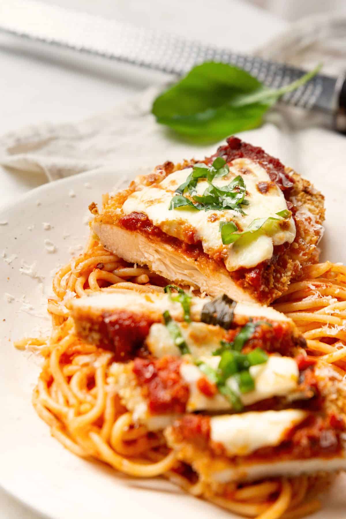 Sliced air fryer chicken parmesan over spaghetti, showing juicy chicken, crispy coating, marinara, and melted mozzarella.