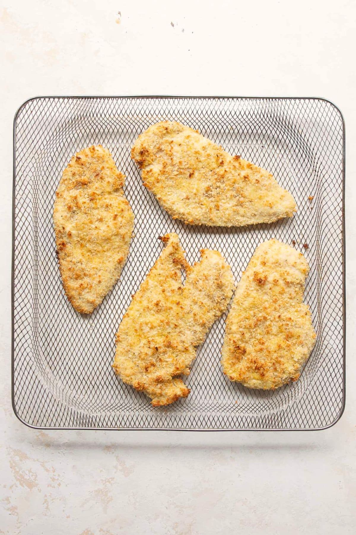 Golden, crispy breaded chicken cutlets in the air fryer after the first cook cycle.