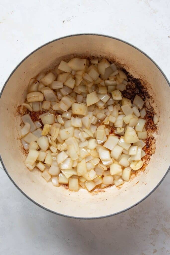 Diced onions sautéing in a Dutch oven for healthy beef stew.