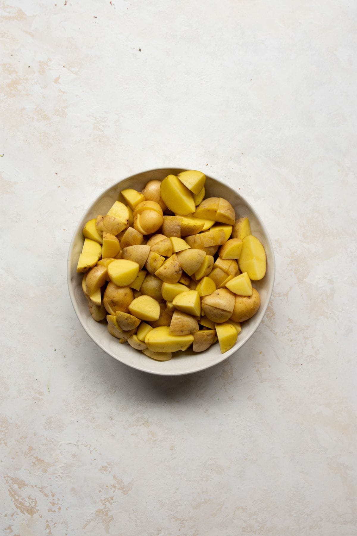 Quartered Yukon gold potatoes in a bowl before roasting.