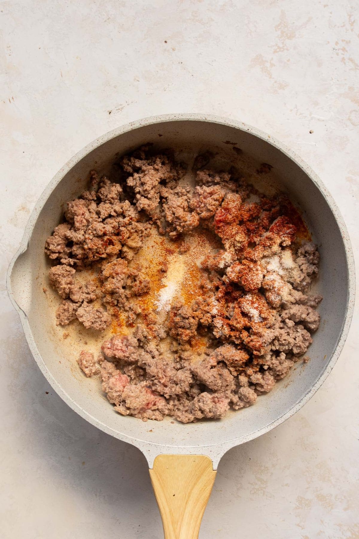 Ground beef cooking in a skillet with seasonings.