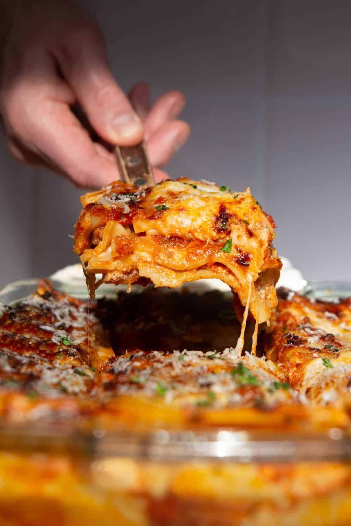 Slice of healthy cottage cheese lasagna lifted from baking dish with melted cheese stretching.