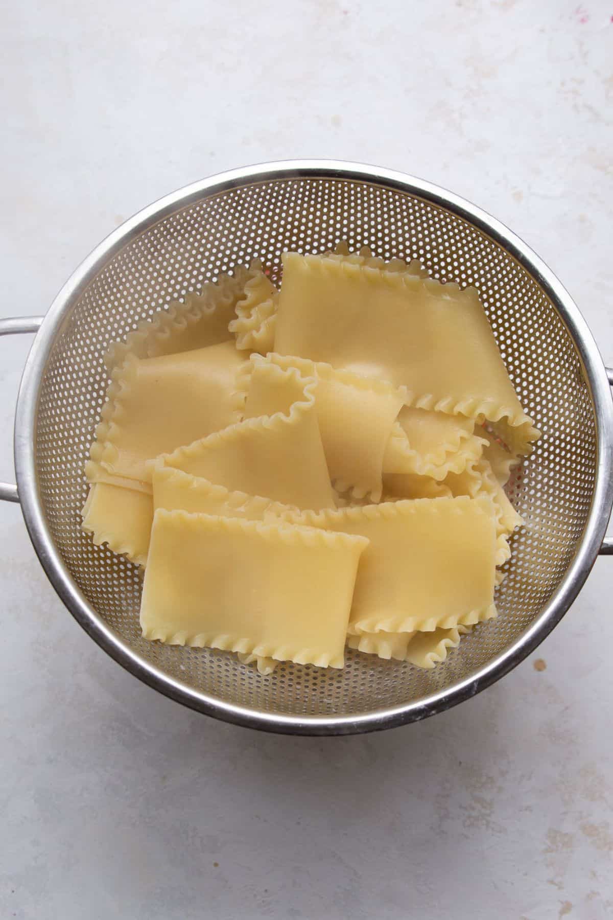 Cooked lasagna noodles draining in a colander.
