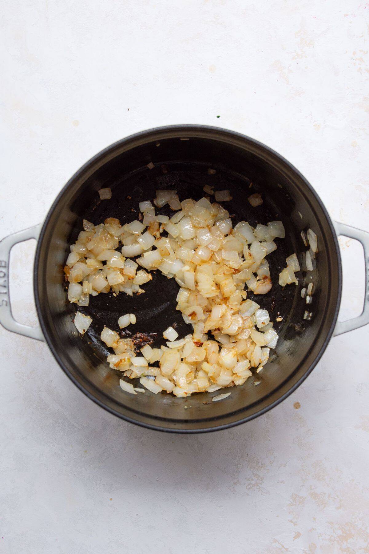 Diced onions sautéing in a pot with olive oil for homemade meat sauce.
