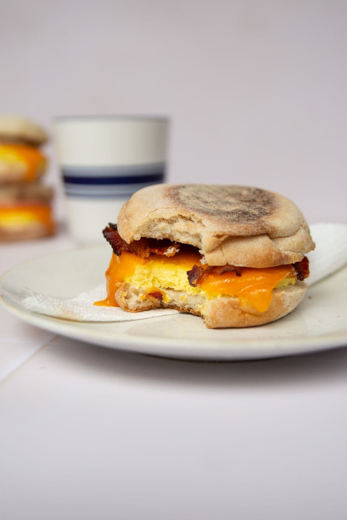 Bit shot of a high-protein freezer breakfast sandwich with fluffy, soft cottage cheese eggs, melted cheese, and turkey bacon on an English muffin.