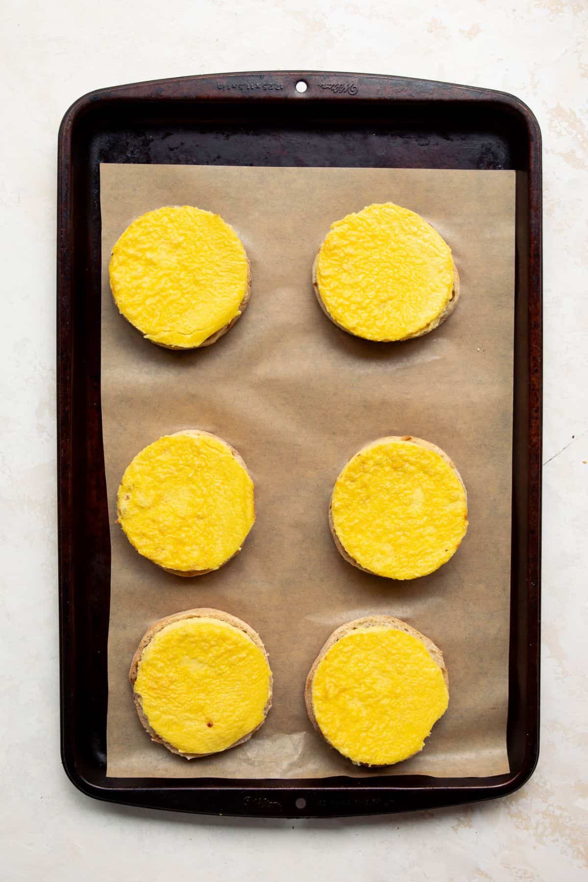 Egg rounds placed on English muffin halves for meal prep breakfast sandwiches.