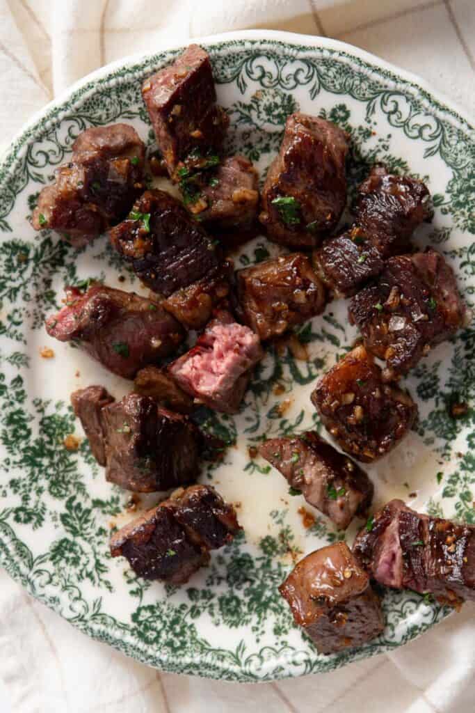 Hot honey garlic butter steak bites served on a plate showing juicy medium rare interior.