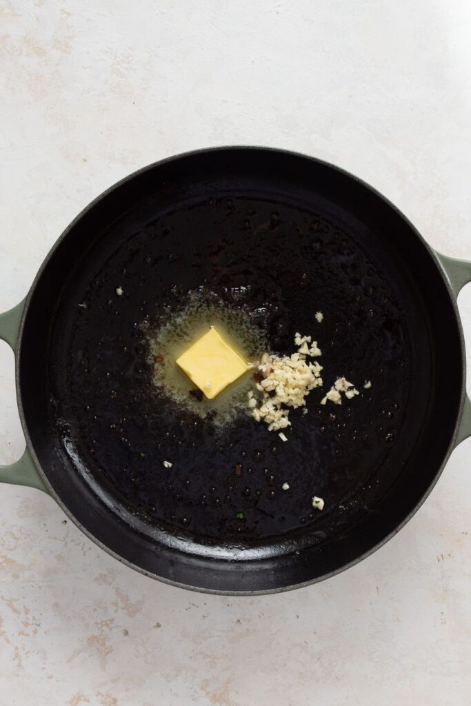 Butter and minced garlic added to cast iron skillet off the heat to make garlic butter sauce.