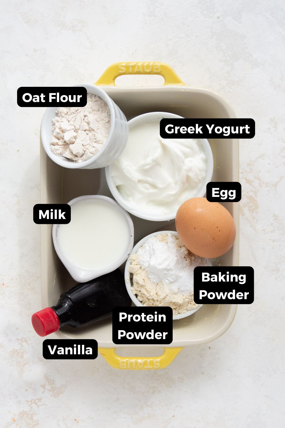 Ingredients for a high protein pancake bowl including oat flour, Greek yogurt, egg, milk, protein powder, baking powder, and vanilla.