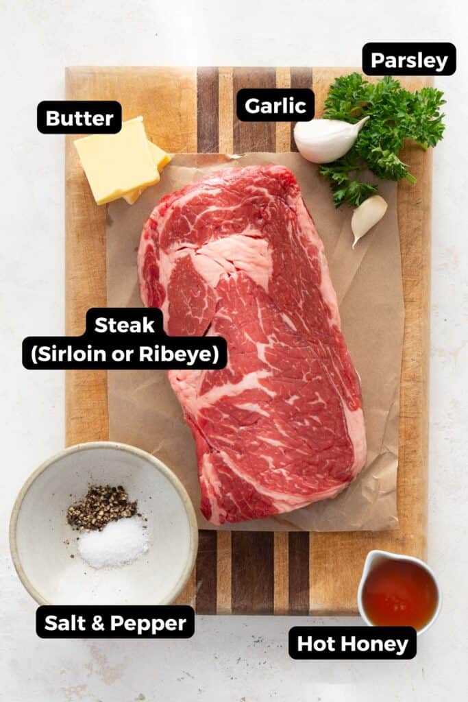 Ingredients for hot honey garlic butter steak bites including sirloin steak, butter, garlic, parsley, salt, pepper, and hot honey.