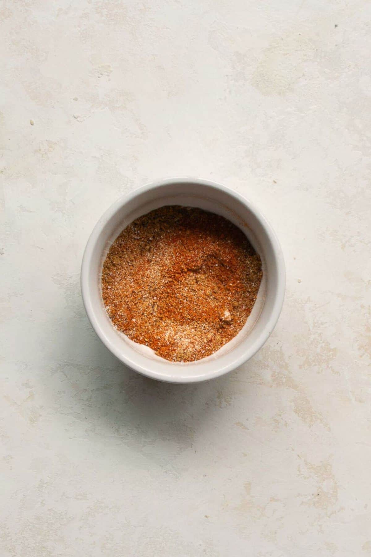 Homemade spice rub for air fryer chicken thighs with smoked paprika, garlic powder, and onion powder in a small bowl.