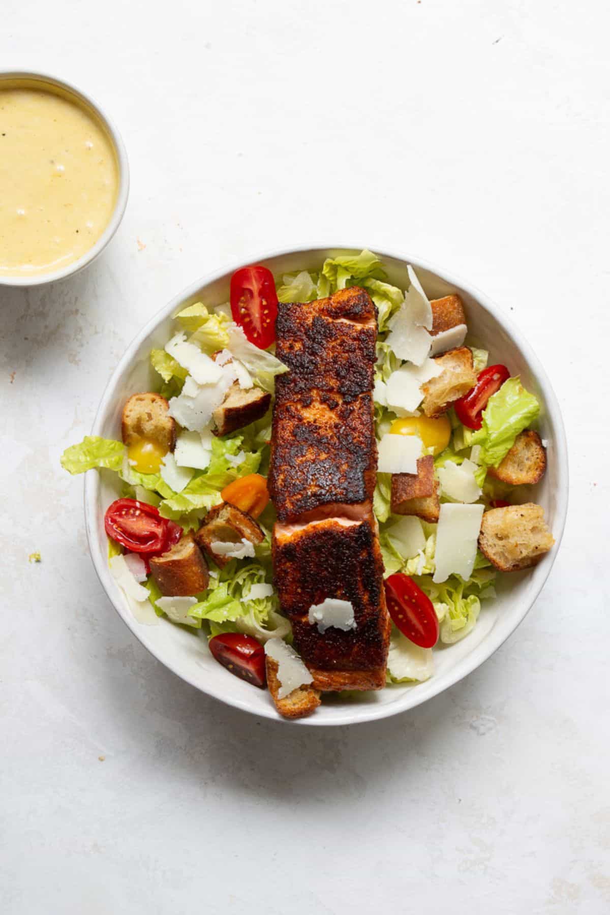 Blackened salmon on top of Caesar salad made with romaine, cherry tomatoes, sourdough croutons, and shaved Parmesan.
