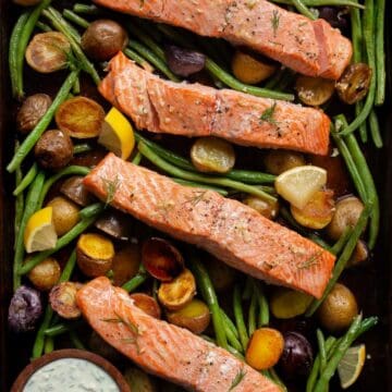 Sheet pan salmon and veggies with lemon garlic potatoes served with tzatziki.