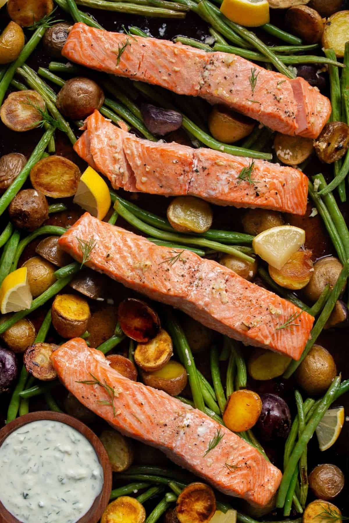 Sheet pan salmon and veggies with lemon garlic potatoes served with tzatziki.