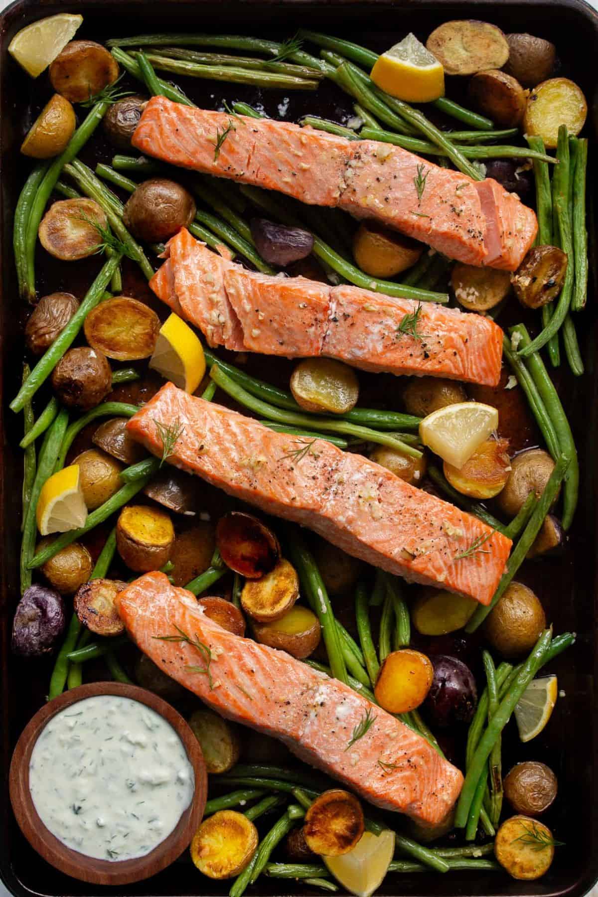 Cooked sheet pan salmon with roasted vegetables and crispy potatoes.